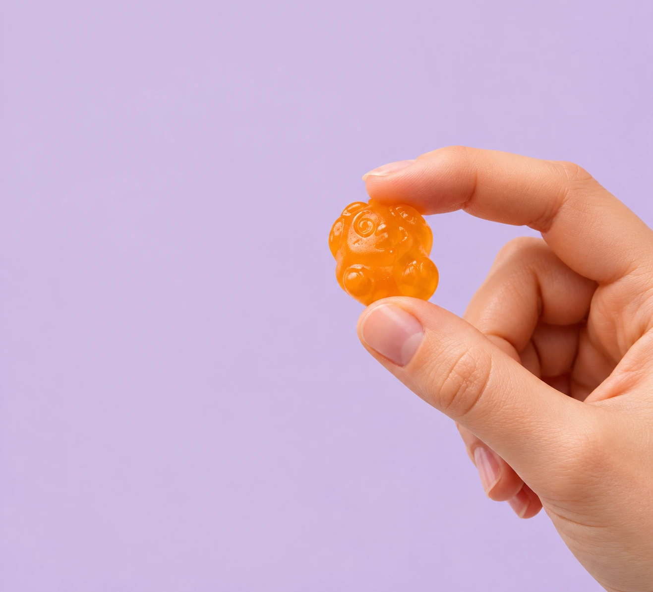 Nærbilde av en hånd som holder en oransje MiniMulti-gummy